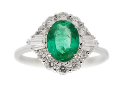 Lot 184 - An 18ct white gold emerald and diamond set cluster ring.