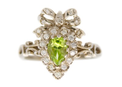 Lot 202 - A 9ct white gold peridot and diamond set bow design dress ring.