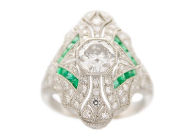 Lot 230 - An Art Deco style platinum diamond and emerald millegrain set dress ring.