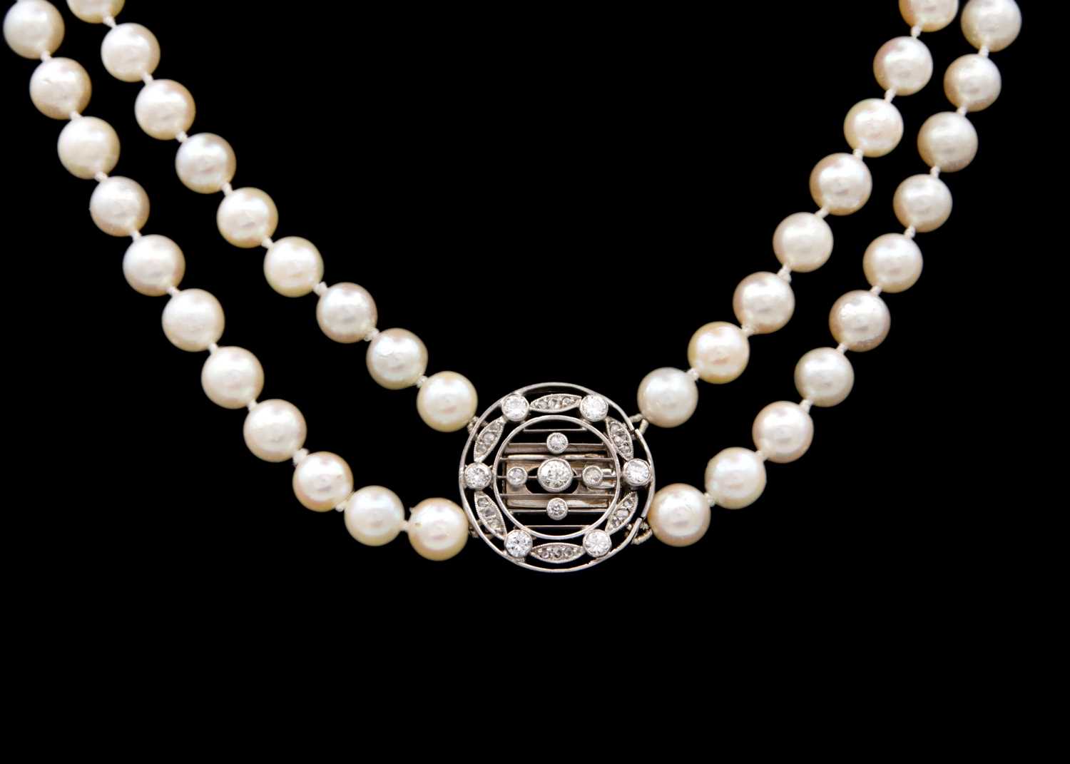 Lot 106 - An early 20th century double-strand white pearl necklace with 18ct white gold diamond set clasp.