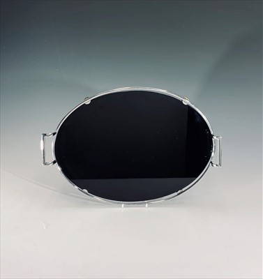 Lot 1064 - An Art Deco style black glass and chrome oval...