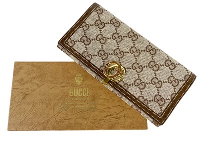 Lot 322 - GUCCI - A wallet in embroidered GG fabric and brown leather trim.