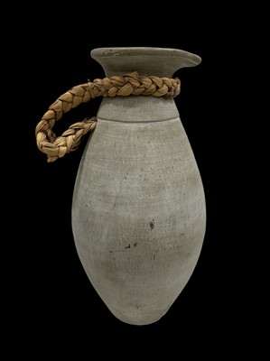 Lot 31 - A heavy ceramic vessel with a woven handle,...