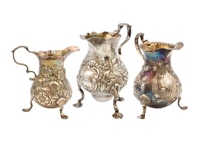 Lot 95 - A selection of three Georgian silver foliate embossed cream jugs.