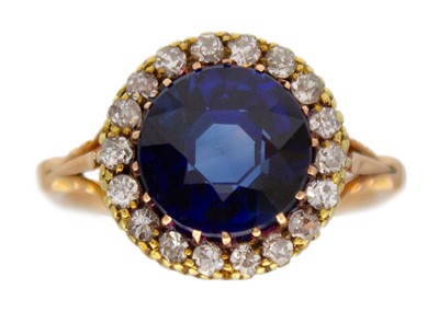 Lot 95 - An 18k rose gold synthetic blue sapphire and diamond set halo ring.