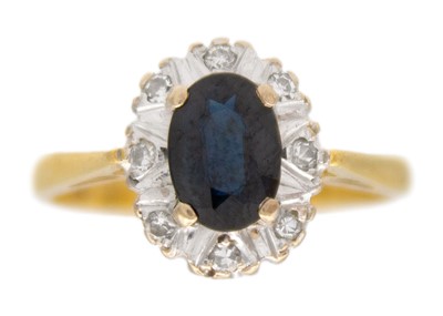 Lot 56 - An 18k gold dark blue sapphire and diamond cluster ring.