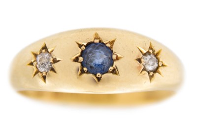 Lot 70 - An 18k gold three-stone sapphire and diamonds gypsy-style band ring.