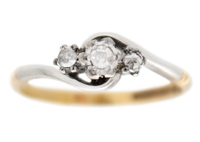 Lot 91 - An early 20th century 9k gold and platinum three-stone diamond crossover ring.