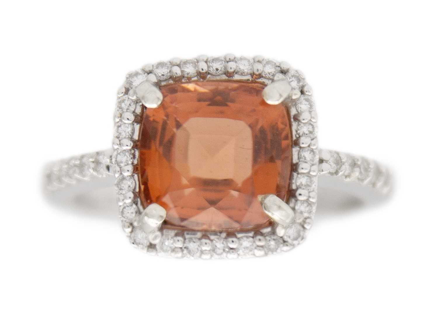 Lot 28 - A pinkish orange tourmaline and diamond set white gold ring.