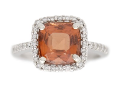 Lot 73 - A pinkish orange tourmaline and diamond 14k gold ring.