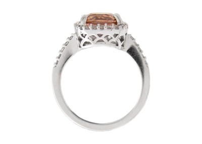 Lot 28 - A pinkish orange tourmaline and diamond set white gold ring.