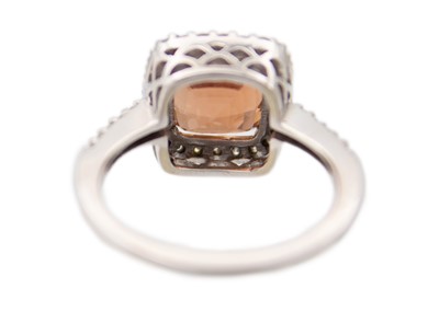 Lot 28 - A pinkish orange tourmaline and diamond set white gold ring.