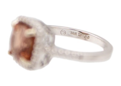 Lot 28 - A pinkish orange tourmaline and diamond set white gold ring.