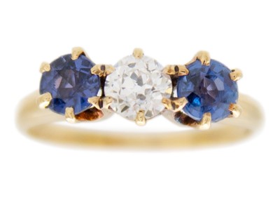 Lot 107 - A three-stone diamond and sapphire 18k yellow gold ring.