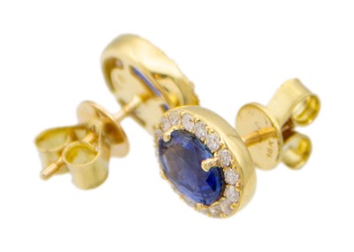 Lot 183 - An attractive pair of 18k two-tone gold oval sapphire and diamond cluster ear studs.