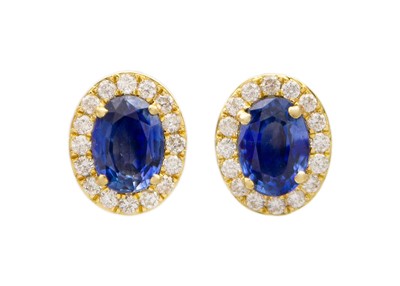 Lot 183 - An attractive pair of 18k two-tone gold oval sapphire and diamond cluster ear studs.