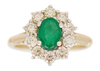 Lot 190 - A 9k white and yellow gold oval emerald and diamond set cluster ring.