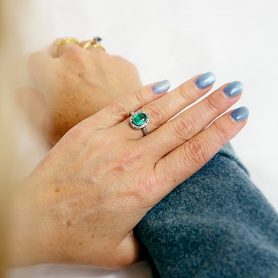 Lot 2 - An emerald and diamond set in a platinum halo ring.