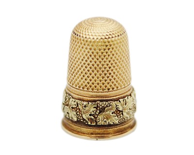 Lot 151 - A fine yellow and green gold thimble, (tests 14k) decorated with a band of fruiting vine.
