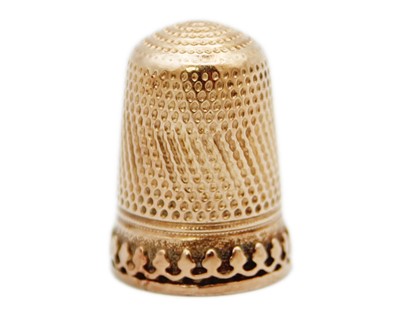 Lot 154 - A rose gold (tests 14k) thimble with scalloped band.