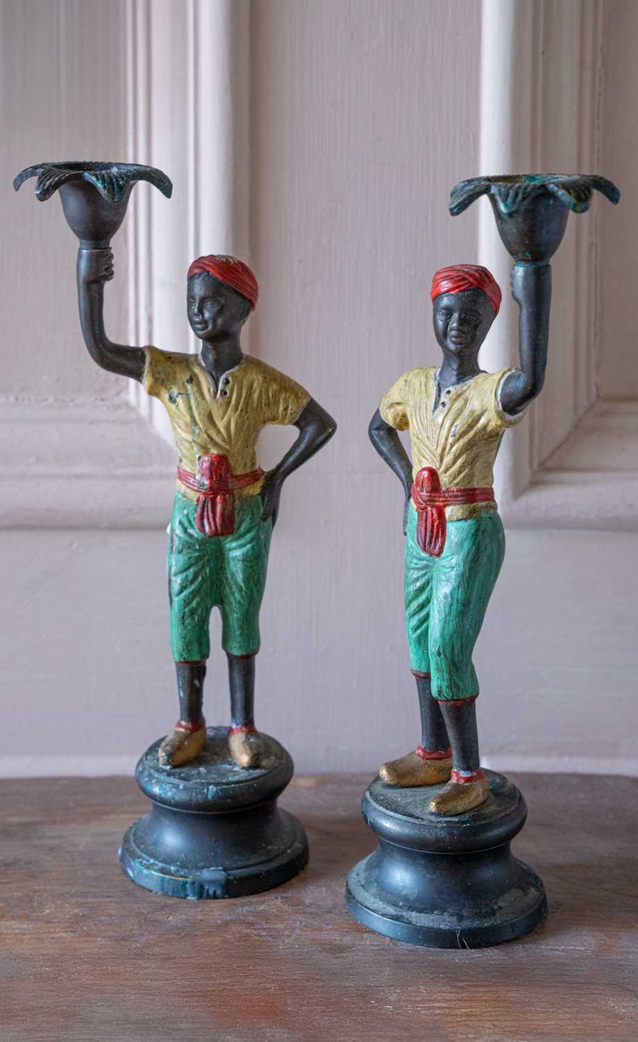 Lot 49 - A pair of cast metal figural candlesticks.
