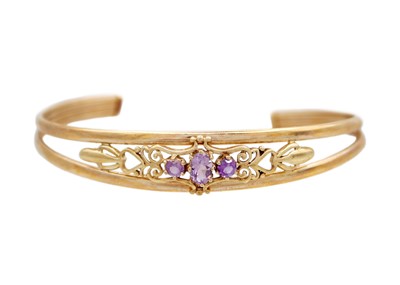 Lot 21 - A 9k gold and amethyst set open bangle.
