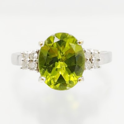 Lot 143 - A 9k white gold, peridot, and diamond ring.