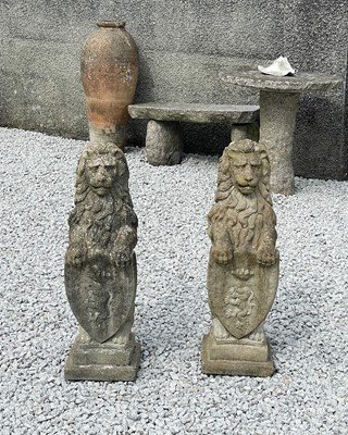 Lot 763 - A pair of reconstituted stone sculptures of lions sejant, each holding a shield.