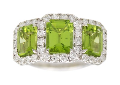 Lot 92 - A 9k white gold, peridot, and diamond cluster dress ring.
