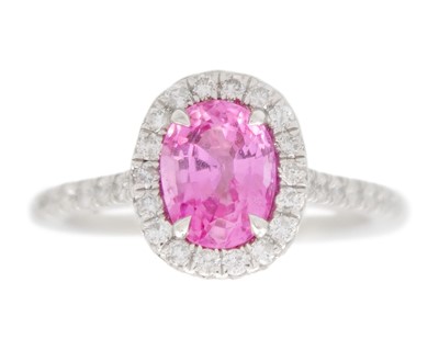 Lot 65 - A pink sapphire and diamond halo ring in platinum.