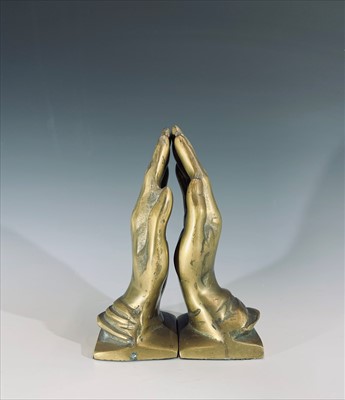 Lot 301 - A pair of brass bookends cast as praying hands,...