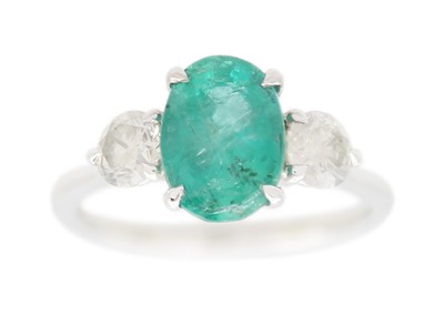 Lot 129 - A three-stone emerald and diamond ring set in platinum.