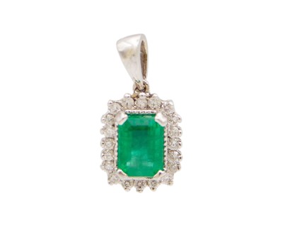 Lot 198 - An 18k white gold, emerald, and diamond cluster pendant.