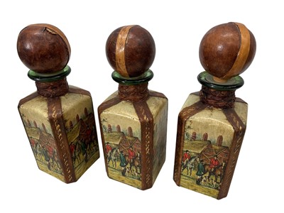 Lot 18 - A set of three leather-wrapped glass decanters...