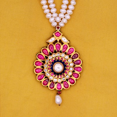Lot 38 - A traditional Indian 22k gold, ruby, and white sapphire pendant on a pearl kundan necklace.