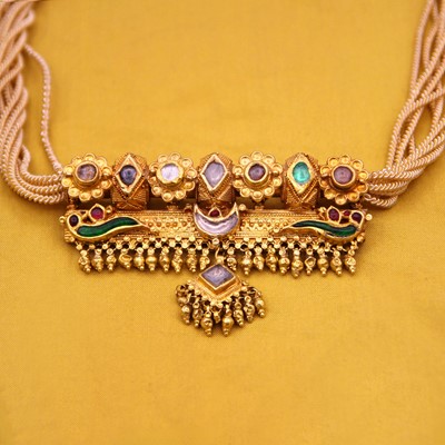 Lot 39 - A traditional Indian 22k gold, white sapphire, ruby, and enamel Dholna pendant on a rope.