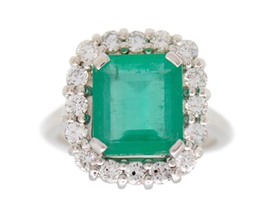 Lot 110 - An 18k white gold, emerald, and diamond halo ring.