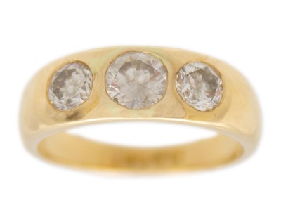 Lot 128 - An 18k gold three-stone diamond band ring.