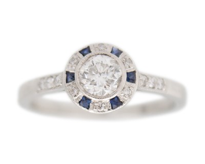 Lot 138 - An 18k white gold diamond and sapphire target-style ring.