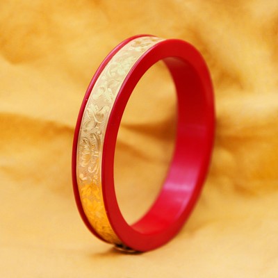 Lot 31 - An Indian 22k gold bangle on a red resin frame.