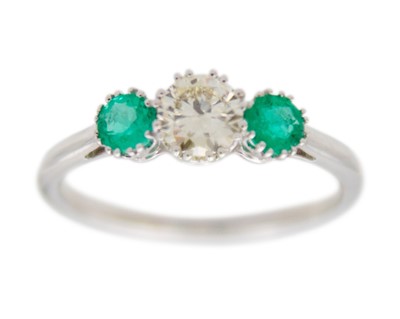 Lot 57 - An 18k white gold three-stone emerald and diamond ring.