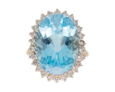 Lot 60 - An 18k gold, blue topaz and diamond halo dress ring.