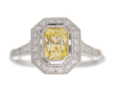 Lot 63 - A yellow sapphire and diamond halo ring set in platinum.