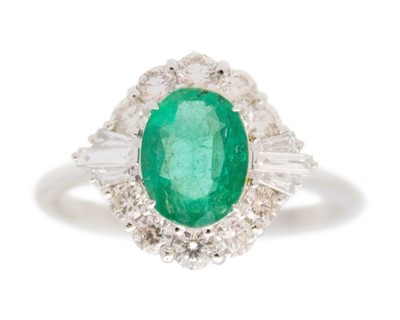 Lot 66 - An 18k white gold emerald and diamond cluster ring.