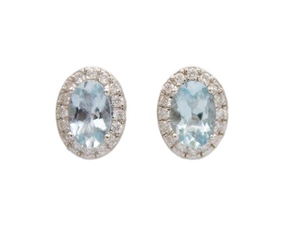 Lot 72 - A pair of 9k white gold aquamarine and diamond halo stud earrings.