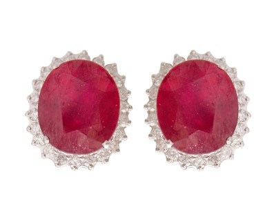 Lot 87 - A pair of large 18k white gold ruby and diamond halo stud earrings.