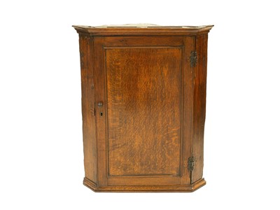 Lot 884 - A George III oak hanging corner cupboard.