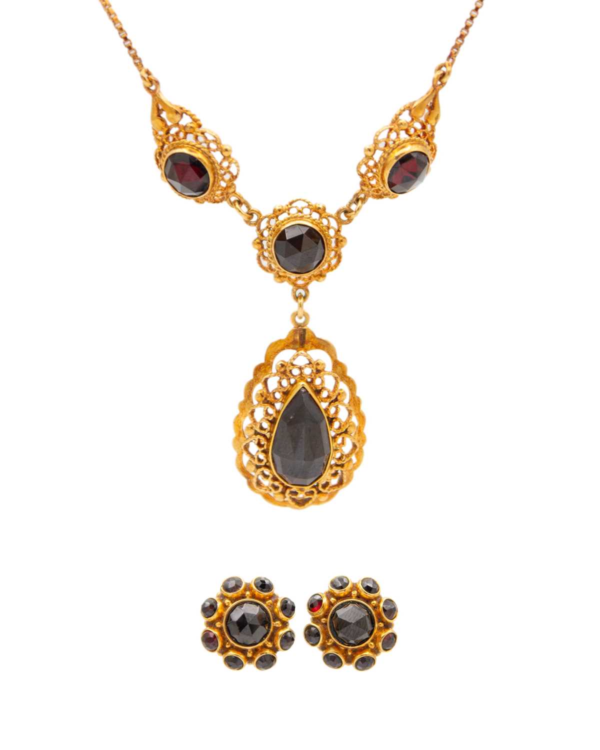 Lot 23 - A 14k rose gold and garnet pendant necklace with a pair of matched earrings.