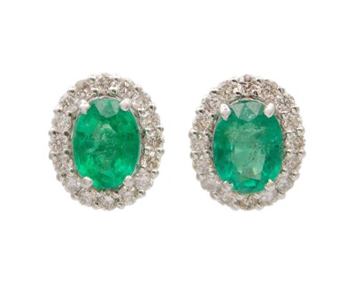 Lot 140 - A pair of 18k white gold emerald and diamond cluster stud earrings.