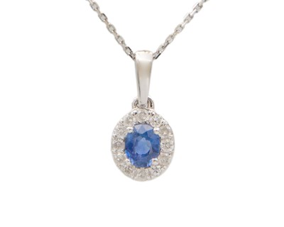 Lot 187 - A 9k white gold oval blue sapphire and diamond cluster pendant, on a fine 9k chain.
